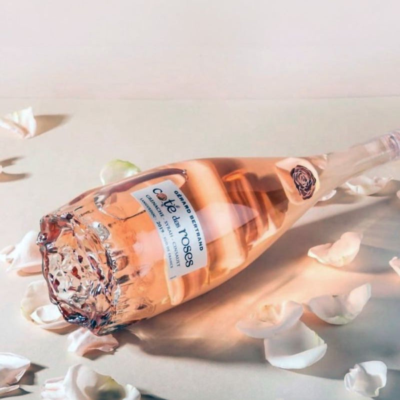 Bottle of rose wine on a light background with white flowers