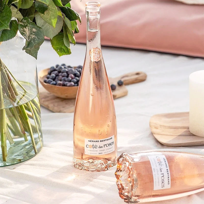 Bottle of Céte des Roses rosé wine on a table with a pink background