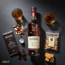 Load image into Gallery viewer, Glenfiddich 15-year-old single malt whisky bottle with Bennetts Dark chocolate, nuts, and 36 Degrees Vanilla fudge on a dark surface