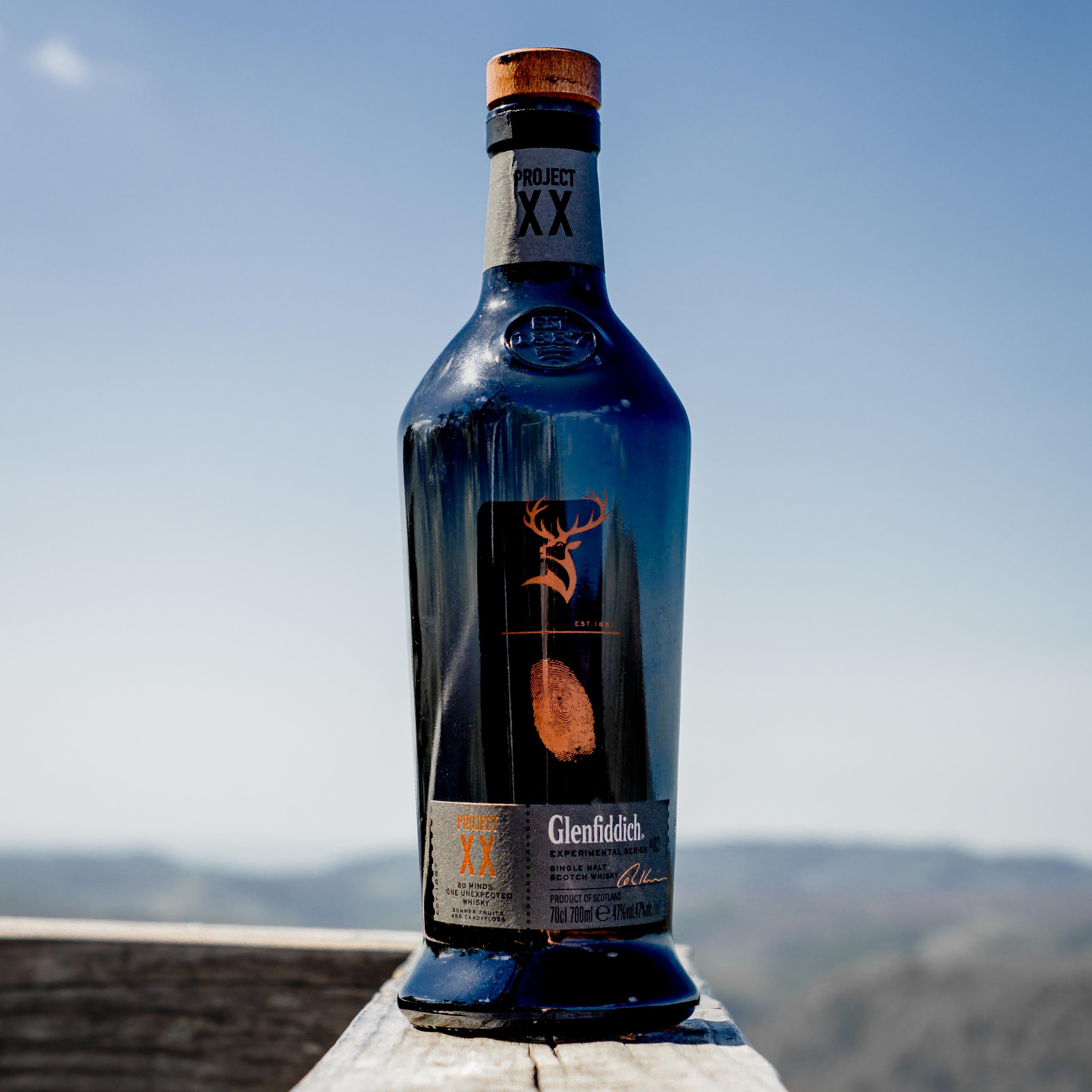 Load image into Gallery viewer, Bottle of Glenfiddich XX Project whisky on a wooden ledge with a scenic background.