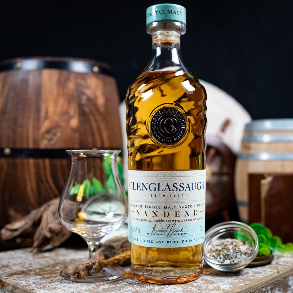 Bottle of Glenglassaugh Sandend whisky with a glass and barrel in the background