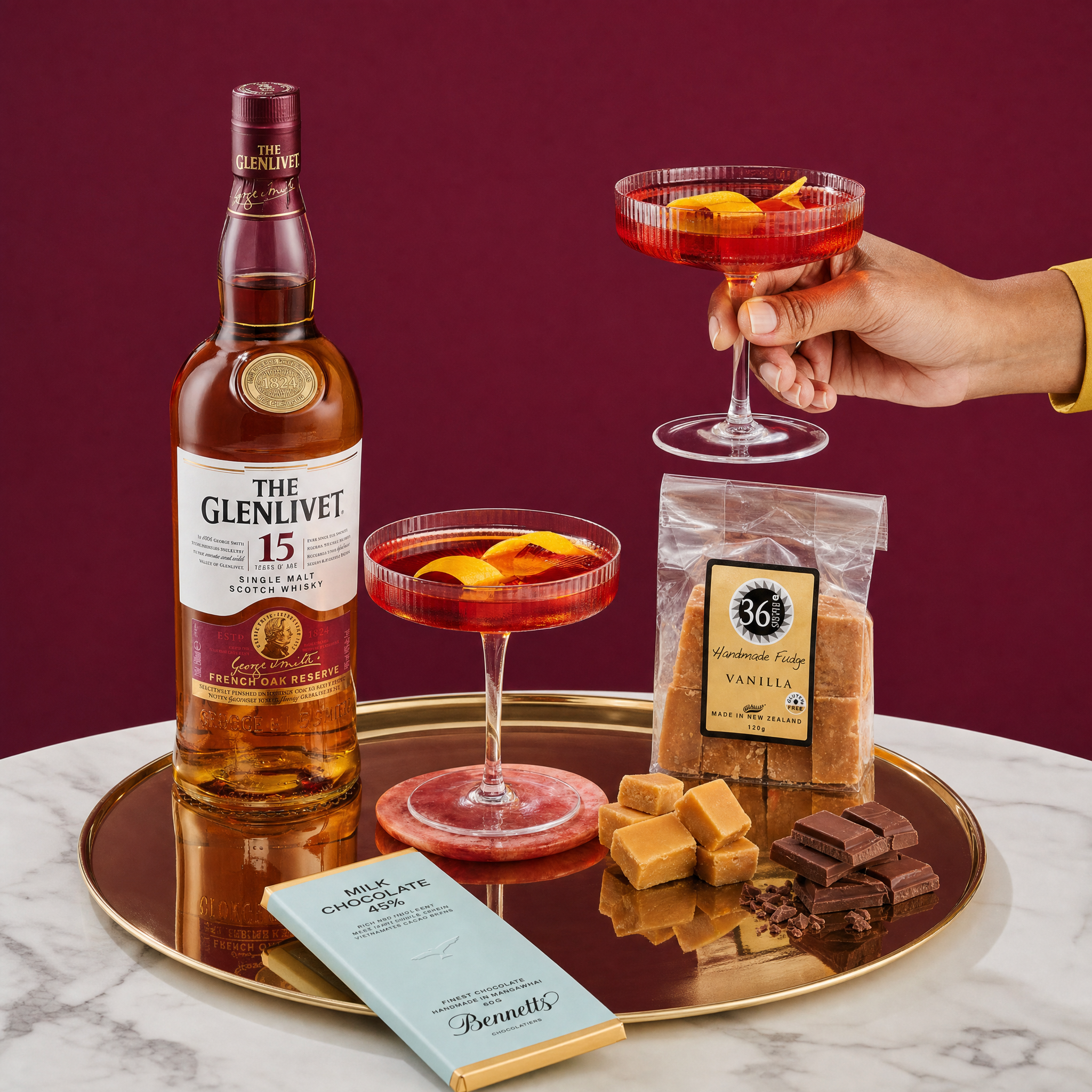 Load image into Gallery viewer, Glenlivet 15 year old whiskey bottle with cocktails and chocolate on a tray against a red background