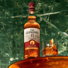 Load image into Gallery viewer, Bottle of The Glenlivet 15-year-old whisky with a glass on a green marble surface
