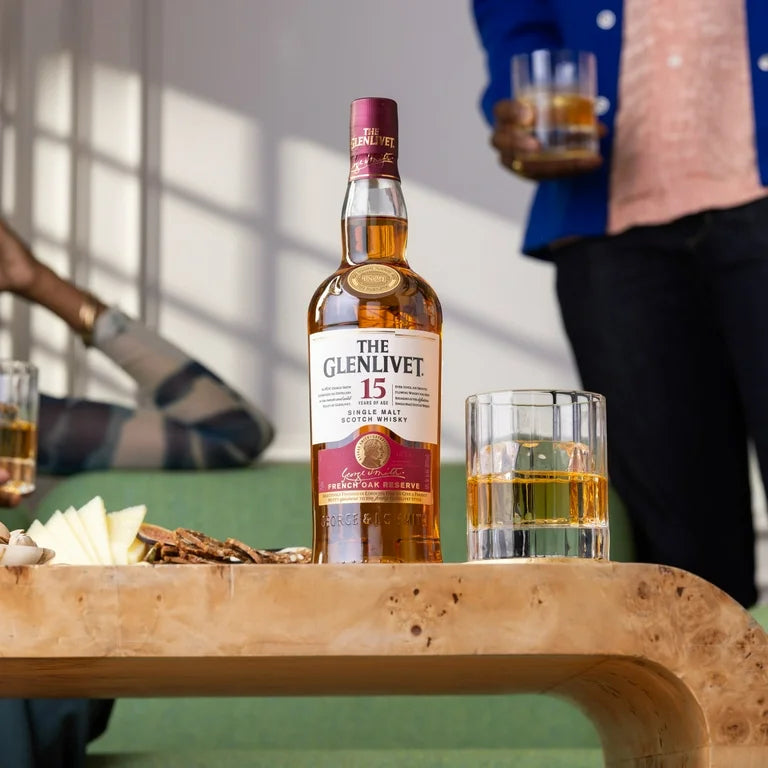 Load image into Gallery viewer, Glenlivet 15 year old whisky on a table with a man behind holding a glass of whisky