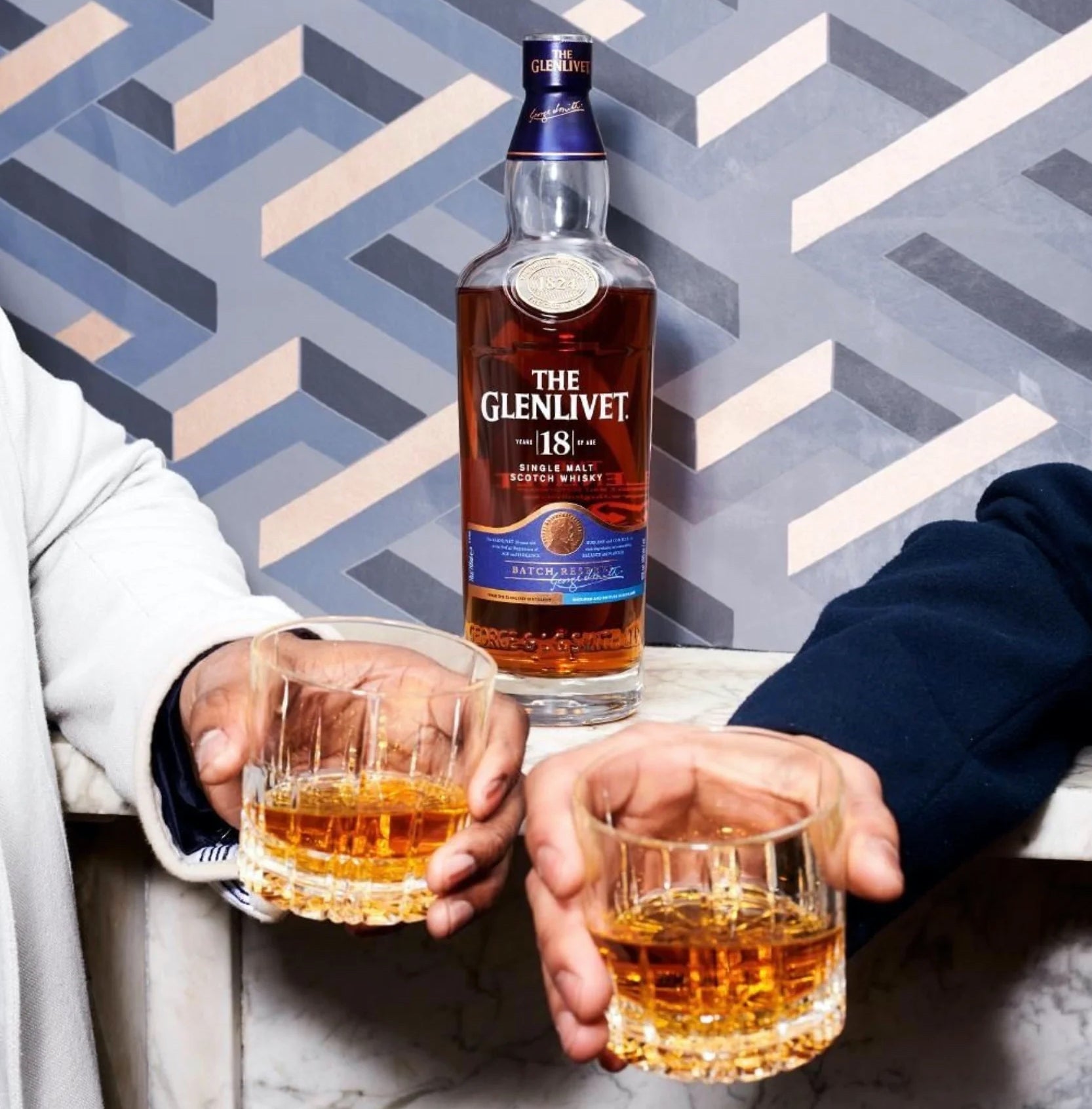 Load image into Gallery viewer, Glenlivet 18YO Single Malt Whisky on a marble table with a couple of men making a toast with two glasses in front of the bottle