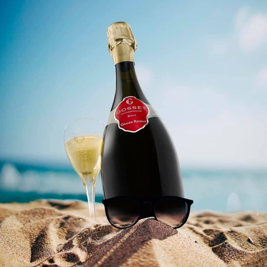 Load image into Gallery viewer, Bottle of Gosset Brut Reserve champagne and glass on sand with ocean background