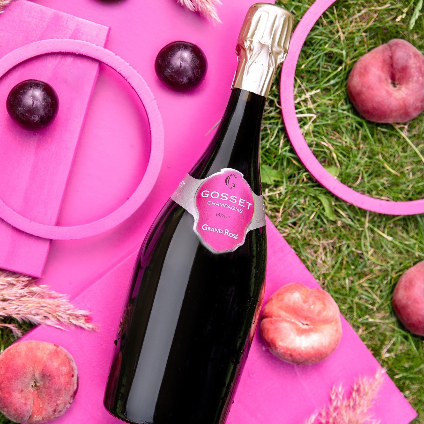 Load image into Gallery viewer, Bottle of Gosset rosé champagne on a pink surface with peaches and plums.