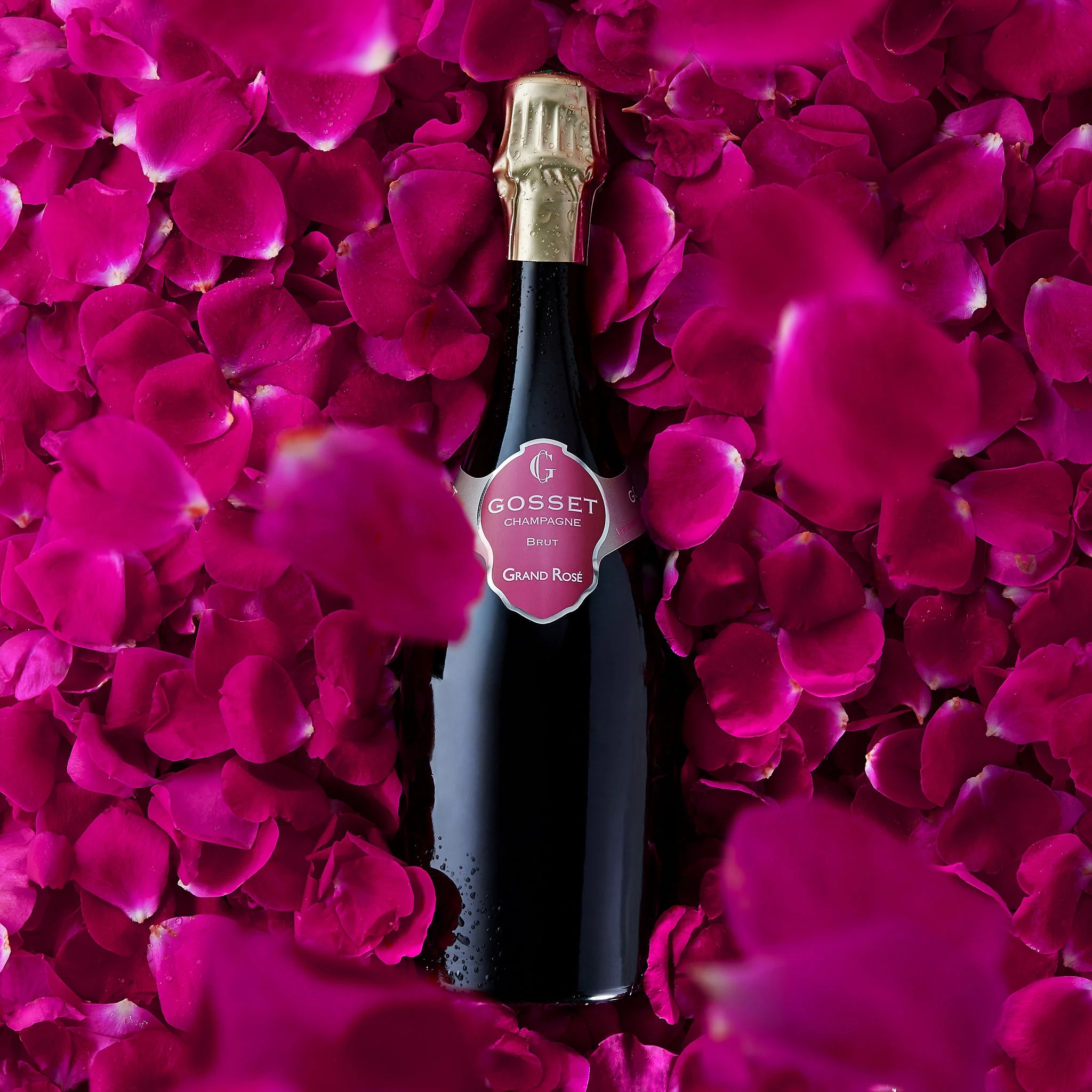 Load image into Gallery viewer, Bottle of Gosset rosé champagne surrounded by pink rose petals