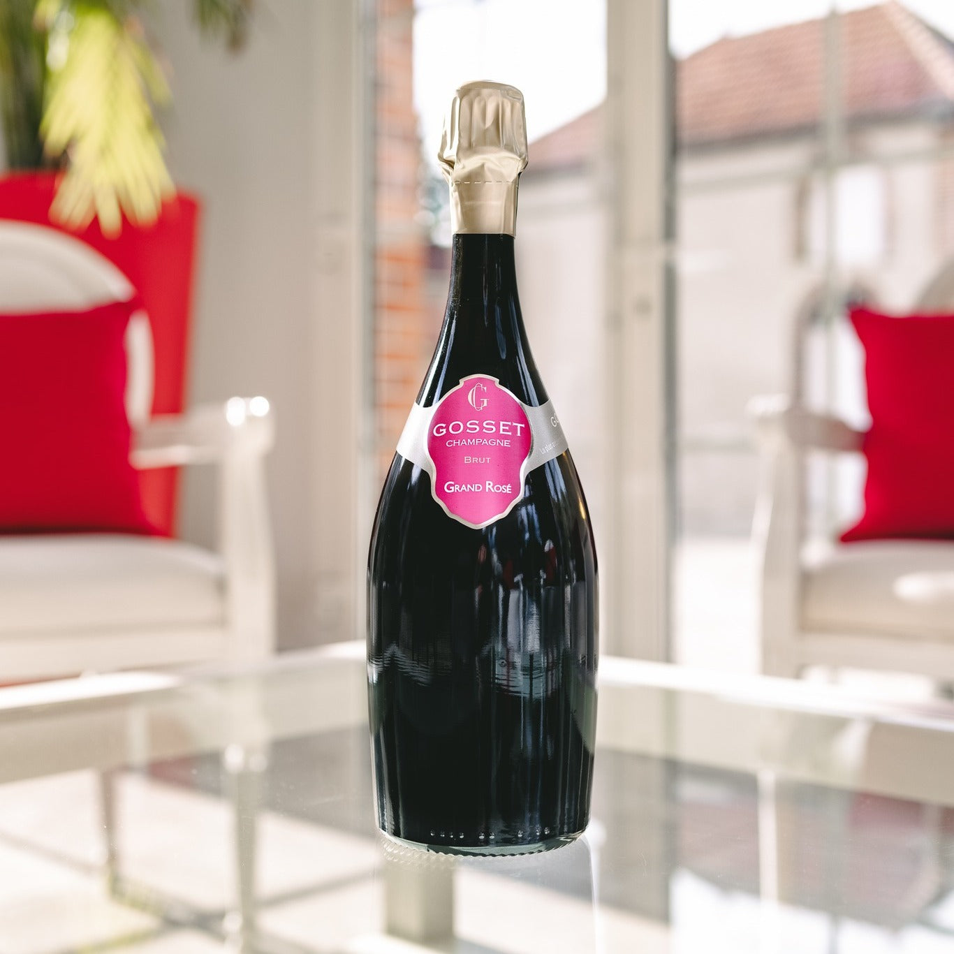 Load image into Gallery viewer, Bottle of Gosset rosé champagne on a glass table with outdoor furniture in the background