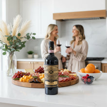 Load image into Gallery viewer, A bottle of Gran Sasso Colline Teramane Montepulciano Alta Quota wine next to a platter of cheese and meat being enjoyed by two women in a modern kitchen