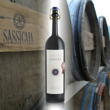 Load image into Gallery viewer, Bottle of Sassicaia grappa with wooden crate and barrels in the background