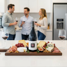 Load image into Gallery viewer, People in a kitchen with a charcuterie board and wine, featuring a bottle of Greywacke-Pinot-Noir wine.