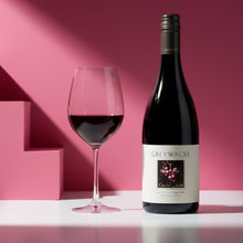 Load image into Gallery viewer, Bottle of Greywacke Pinot Noir wine and a glass with red wine on a pink background