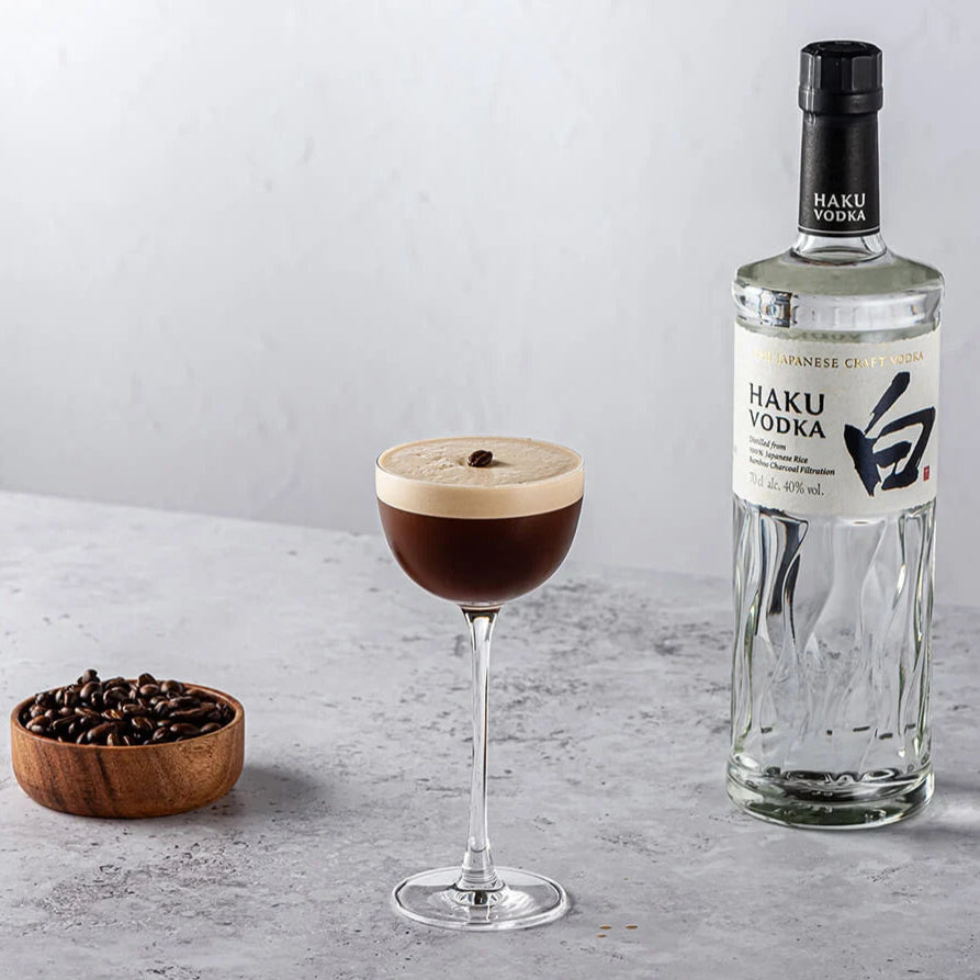 Bottle of Haku Vodka with a cocktail and coffee beans on a gray surface