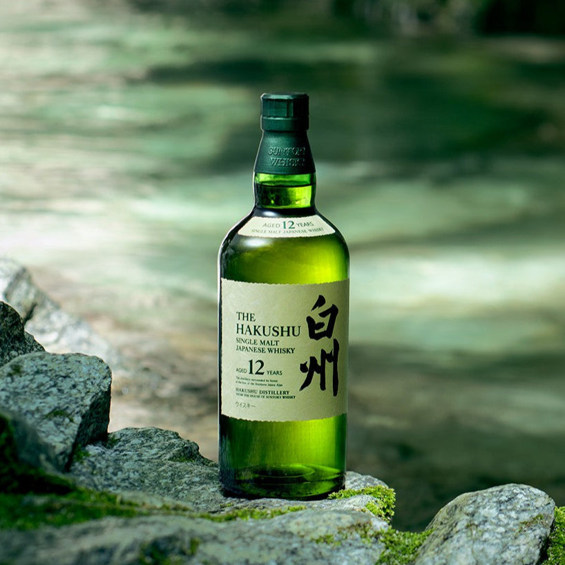 Bottle of Hakushu whisky on a stone with a blurred natural background