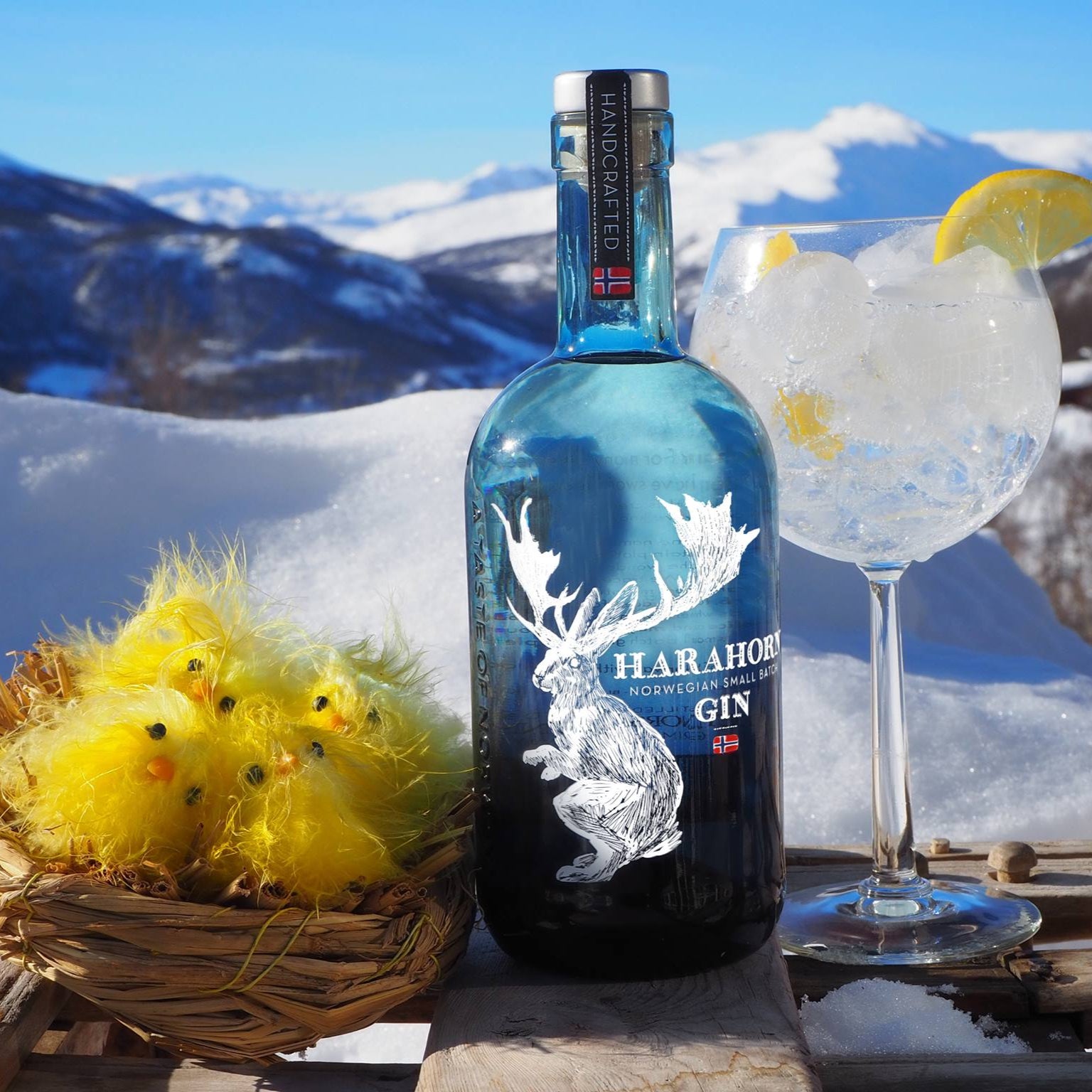 Load image into Gallery viewer, Bottle of Harahorn Gin with a cocktail and decorative birds on a snowy mountain background.