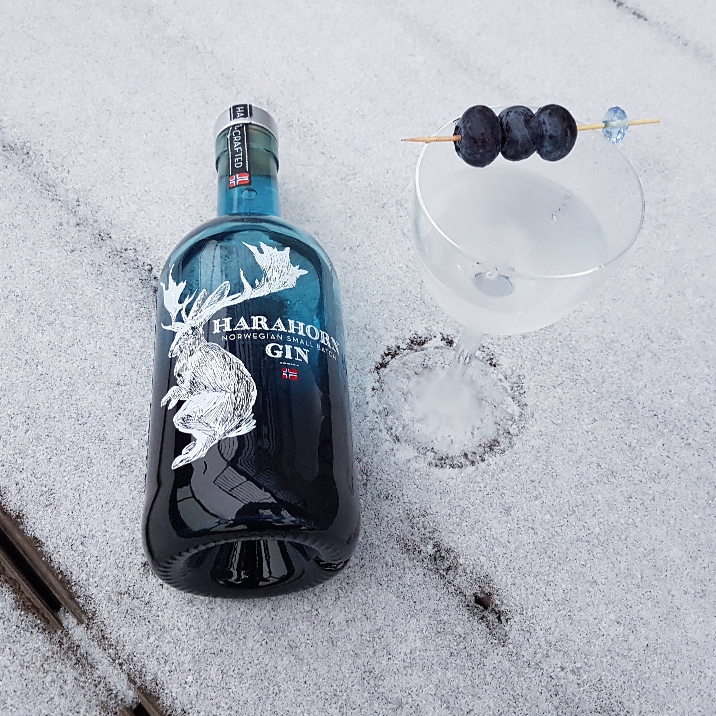 Load image into Gallery viewer, A bottle of Harahorn Gin in snow next to a martini cocktail