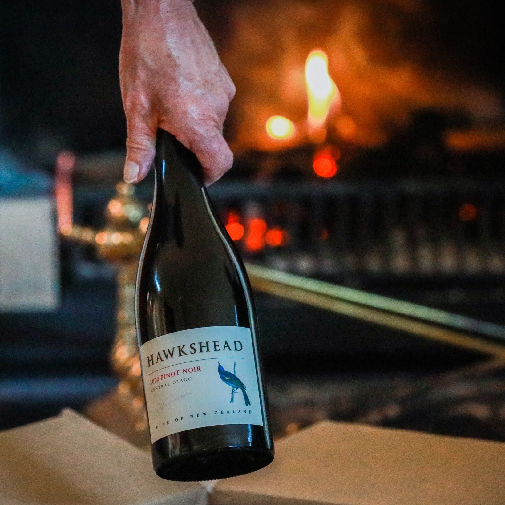 Load image into Gallery viewer, Hawkshead wine bottle held by a hand with a warm, indoor background