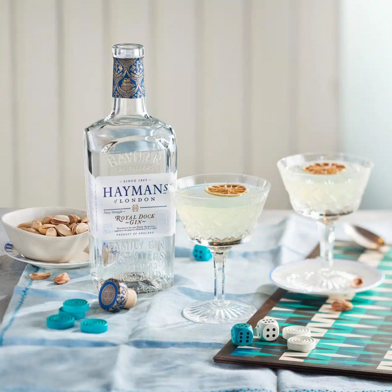 Load image into Gallery viewer, Hayman’s Royal Dock Navy Strength Gin bottle with cocktails and snacks on a table