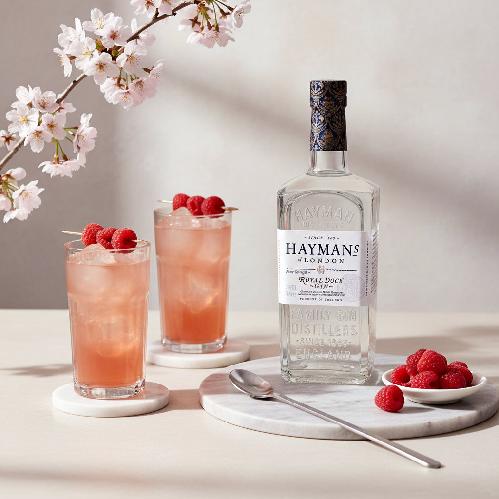 Load image into Gallery viewer, Hayman’s Royal Dock Navy Strength Gin bottle with two cocktails and raspberries on a light background