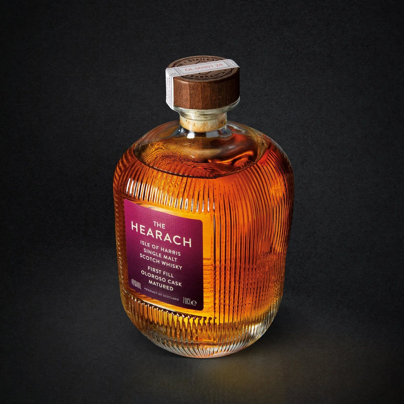 Load image into Gallery viewer, A bottle of The Hearach Oloroso Cask Single Malt Scotch Whisky on a dark studio background. The bottle is made of ribbed clear glass, filled with amber-colored whisky, and features a dark purple label with gold text.