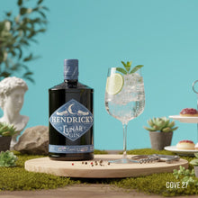 Load image into Gallery viewer, Hendrick's Lunar Gin bottle with a glass of gin and tonic on a decorative table with plants and a blue background.