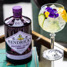 Load image into Gallery viewer, Hendrick&#39;s gin bottle with a cocktail garnished with flowers on a table.