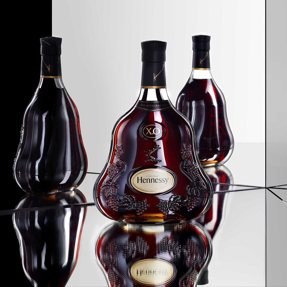 Hennessy XO cognac bottle on a reflective surface with a black and white background