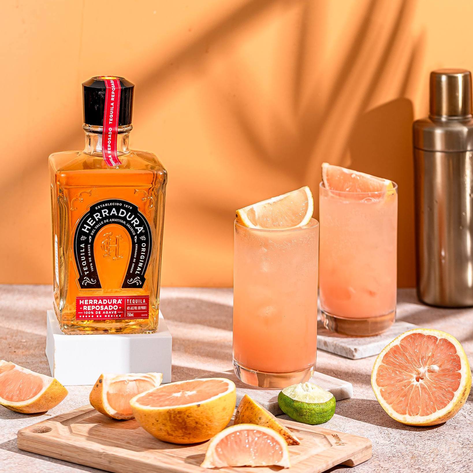 Load image into Gallery viewer, Herradura Reposado tequila bottle with two cocktails and citrus fruits on a wooden surface.