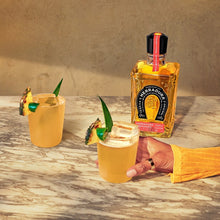 Load image into Gallery viewer, Two yellow Herradura Reposado Tequila cocktails with a bottle of Jose Cuervo on a marble surface.