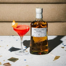 Load image into Gallery viewer, Bottle of Highland Park 12 year old whisky with a cocktail on a patterned surface