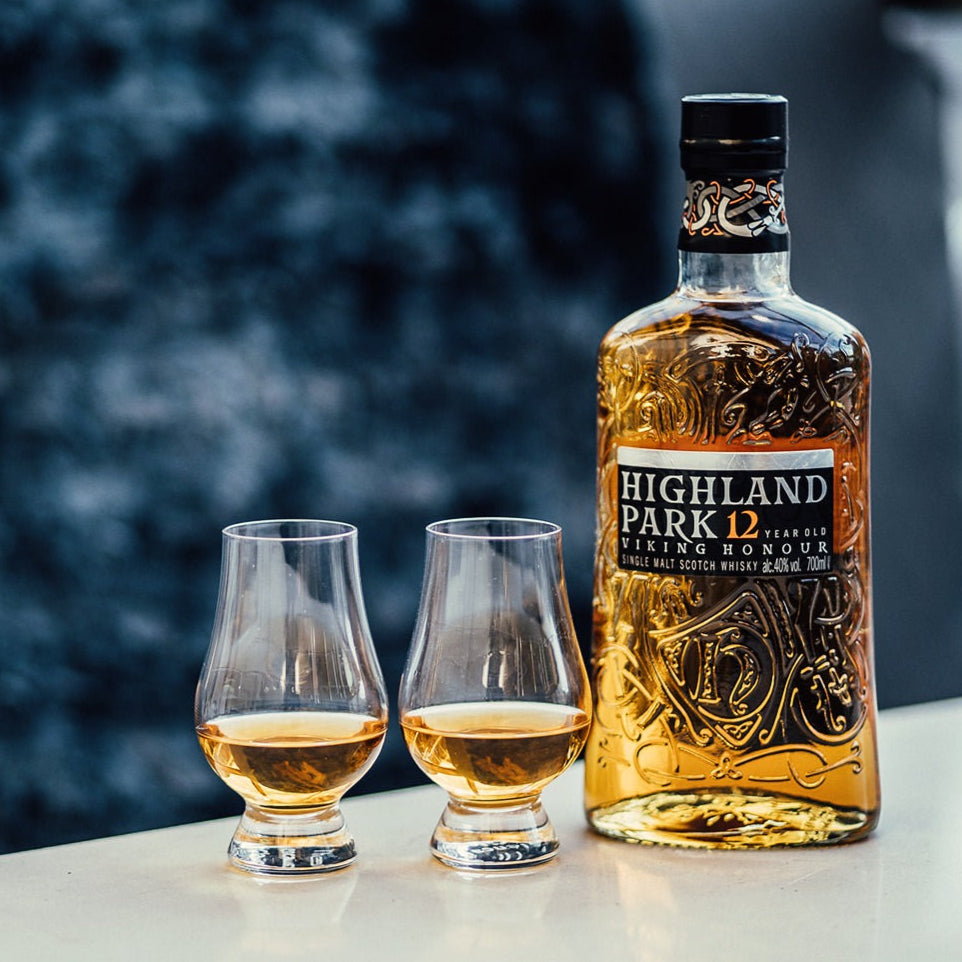 Highland Park whisky bottle with two glasses on a blurred natural background