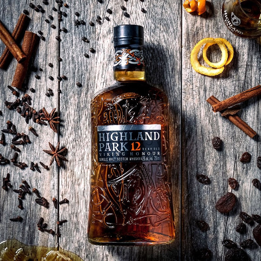 Load image into Gallery viewer, Highland Park 12 year old Viking Honour Whisky on a wood background with spices around the bottle