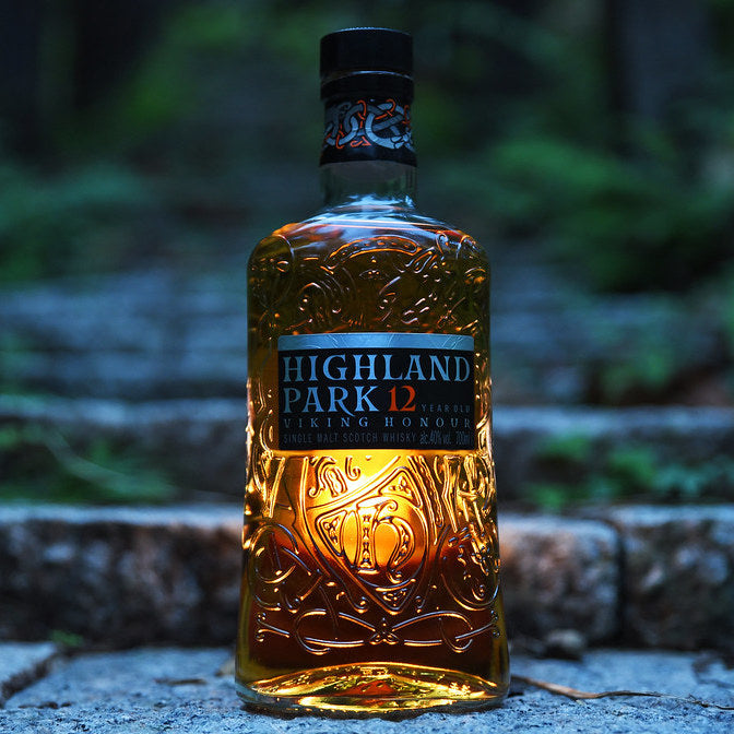 Load image into Gallery viewer, Highland Park 12 year old Viking Honour Whisky in the night outside with a light shining through the bottle