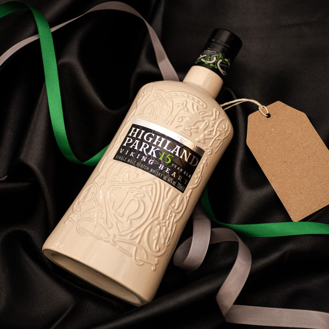 Load image into Gallery viewer, Highland Park whisky bottle with decorative elements on a black fabric background