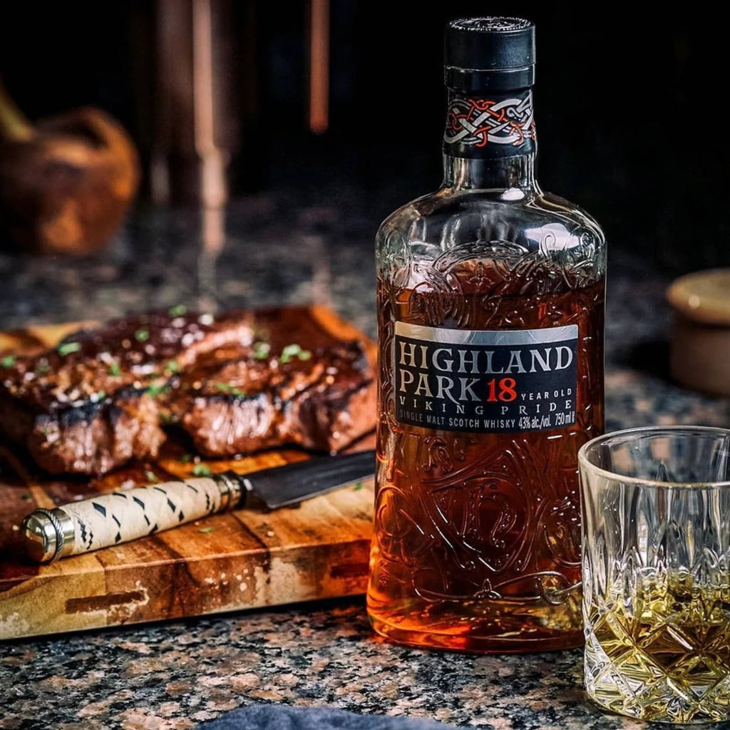 Highland Park 18-year-old whisky bottle with a steak and glass on a table