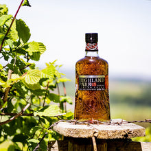 Load image into Gallery viewer, Highland Park 18 whiskey bottle on a wooden post with greenery in the background