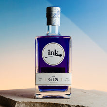 Load image into Gallery viewer, Bottle of ink Gin on a stone surface with a blue and orange gradient background