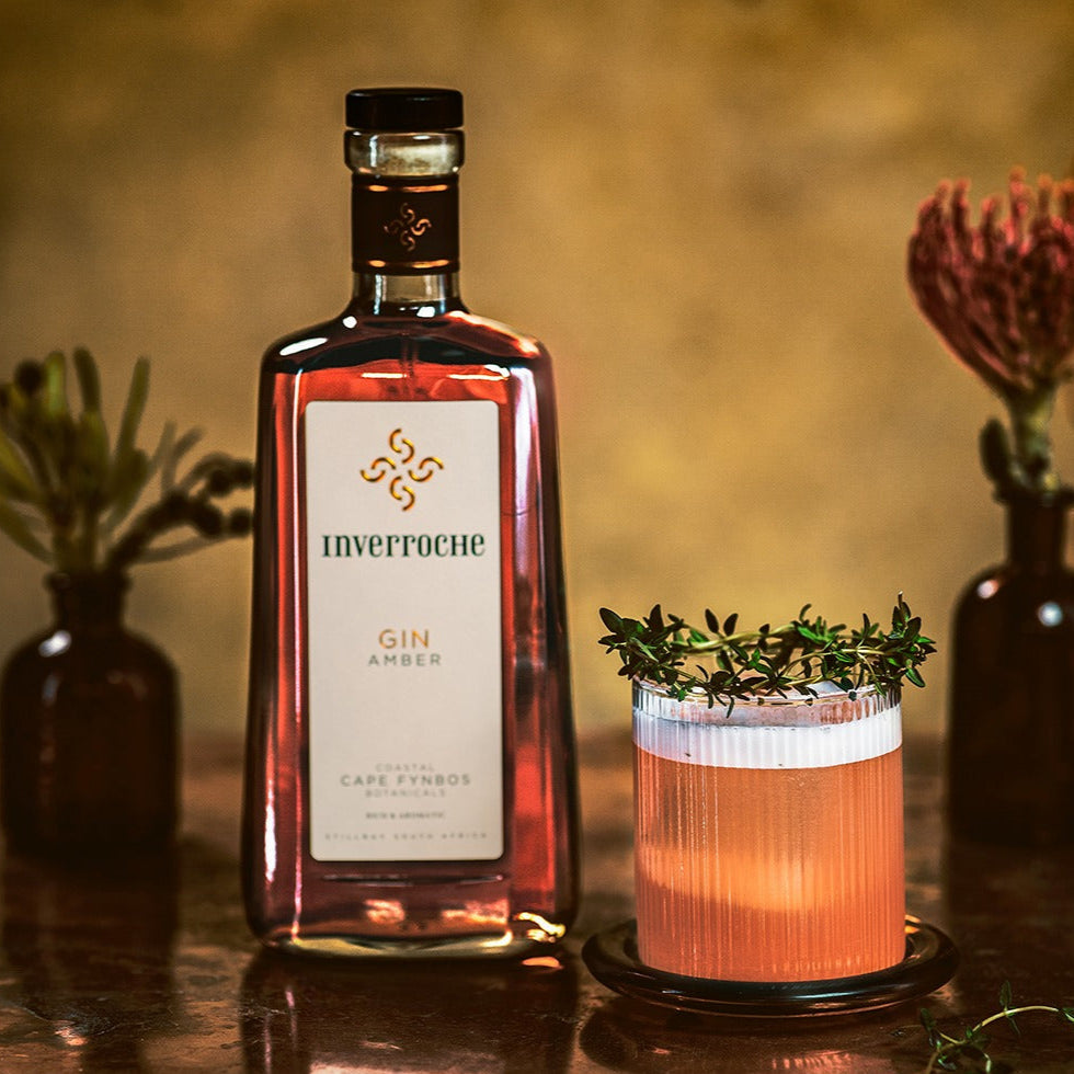 Load image into Gallery viewer, Bottle of Inverroche Gin Amber with a cocktail garnished with thyme on a wooden surface.