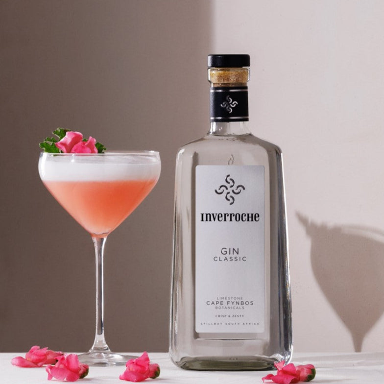 Inverroche Gin bottle with a cocktail and pink flowers on a white surface.