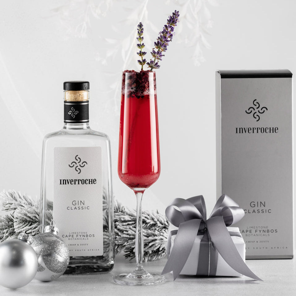 Inverroche gin bottle, glass with red liquid and lavender, and gift box on a light background
