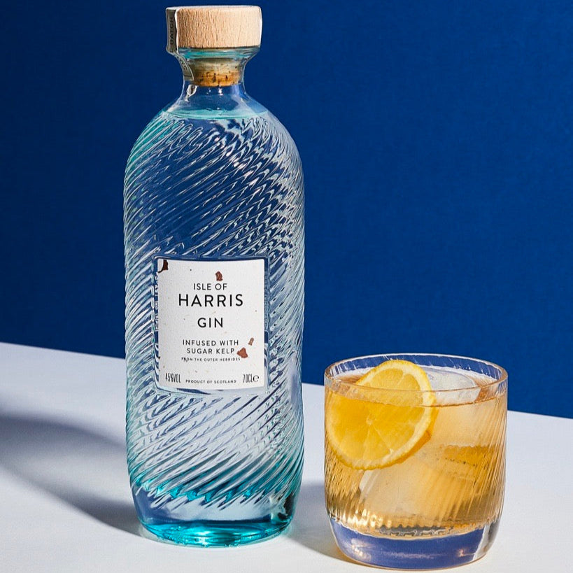 Bottle of Isle of Harris Gin with a glass of gin and tonic on a blue background