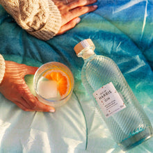 Load image into Gallery viewer, Bottle of Harris Gin and a lit candle on a textured surface