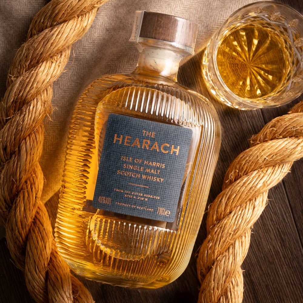 Load image into Gallery viewer, Isle of Harris 'The Hearach' Single Malt Whisky bottle on a wodden table with a tumbler of neat whisky