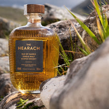 Load image into Gallery viewer, Bottle of The Hearach single malt Scotch whisky on a rocky surface with grass.