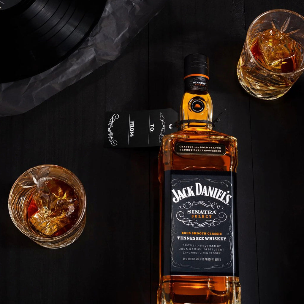 Jack Daniel's whiskey bottle with two glasses of whiskey on a dark surface