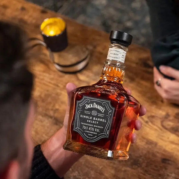 Person holding a bottle of Jack Daniel's whiskey at a bar.