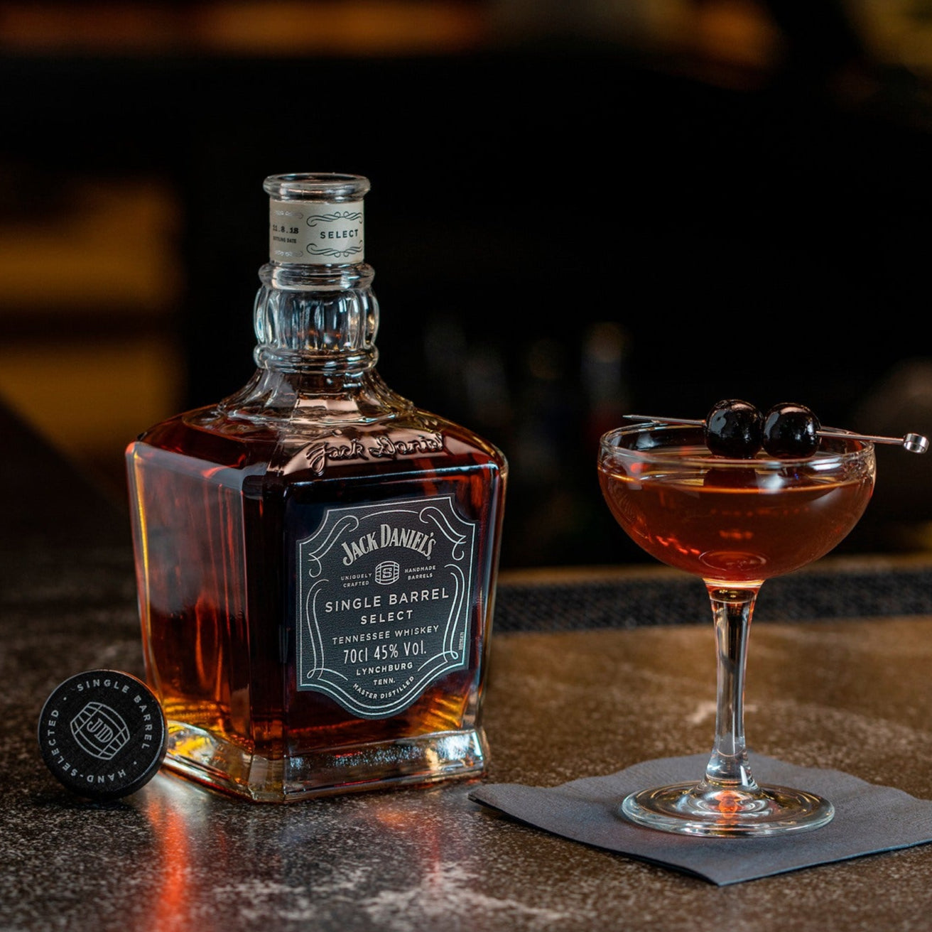 Load image into Gallery viewer, Jack Daniel's whiskey bottle with a cocktail on a bar counter, blurred bar background
