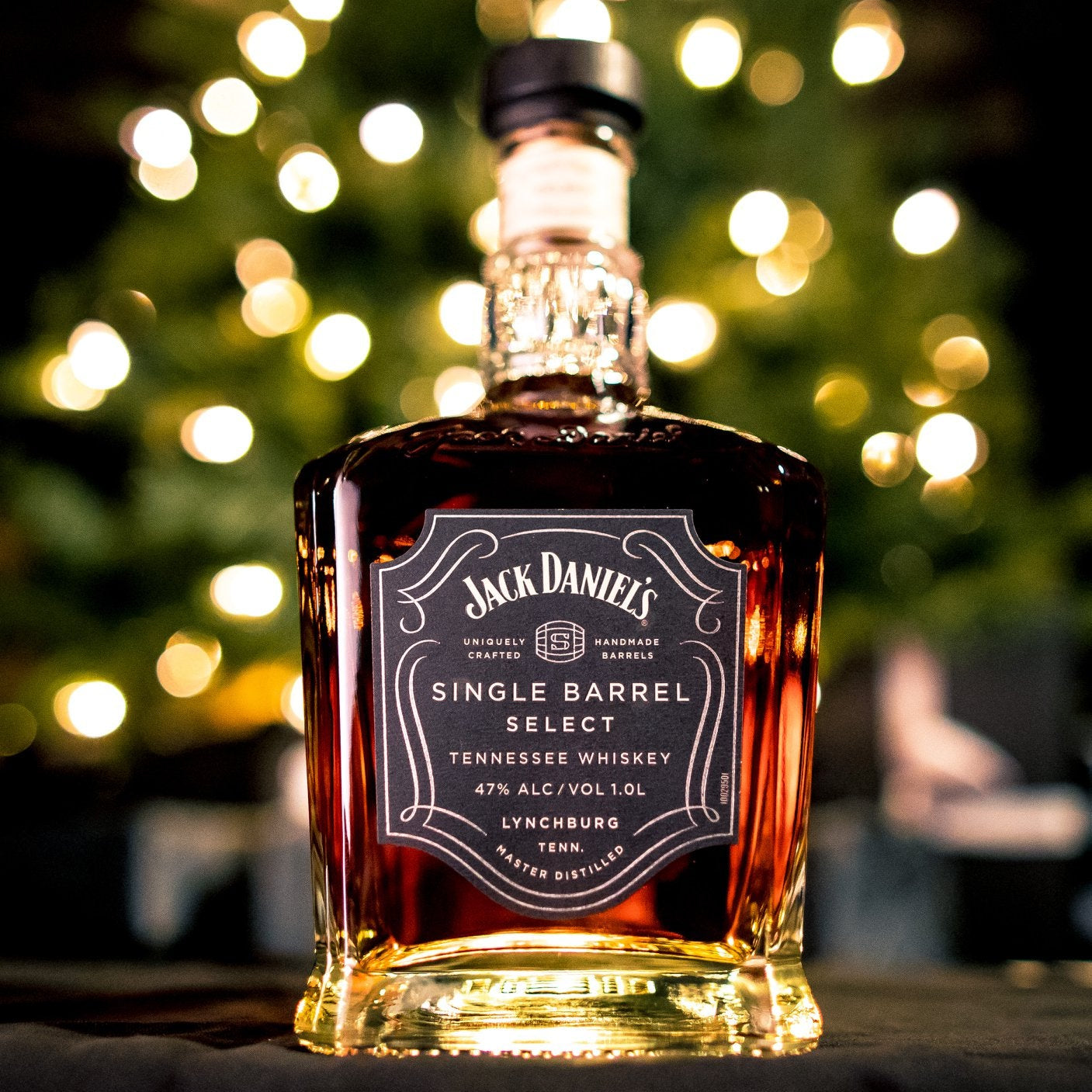 Load image into Gallery viewer, Jack Daniel's Single Barrel Select Tennessee Whiskey bottle with a blurred Christmas tree in the background