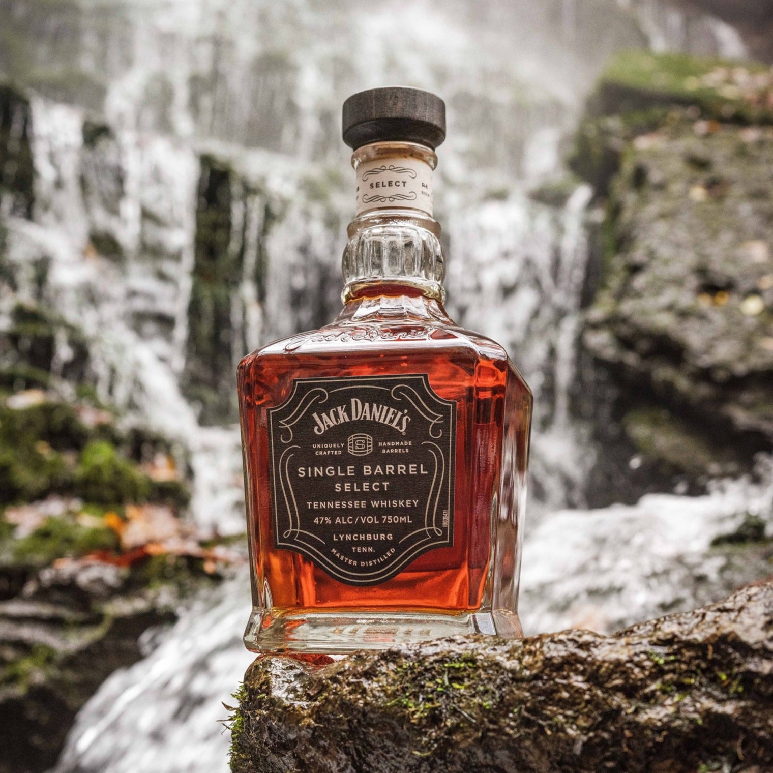 Load image into Gallery viewer, Jack Daniel's Single Barrel whiskey bottle on a rock with a waterfall in the background